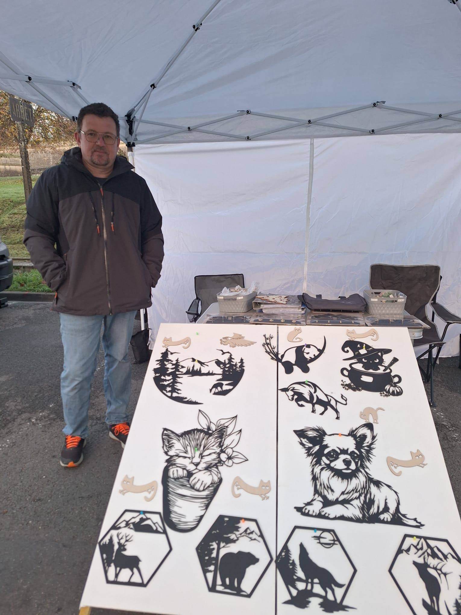 Stand CraftLasArt sur un marché artisanal présentant des décorations murales en bois découpées au laser, créations artisanales exposées en extérieur